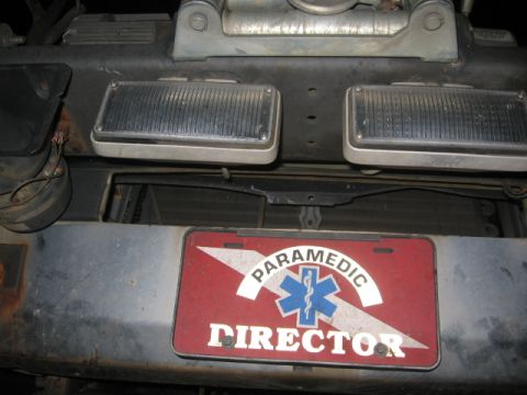 1988 Ford Bronco - A close-up view of a vehicle's front bumper, a "Paramedic Director" license plate and two auxiliary lights.