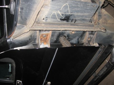 1988 Ford Bronco - Close-up view of the underbody of a black vehicle, showing structural components and a corrugated hose.