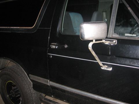 1988 Ford Bronco - Side view of a black 1988 Ford Bronco showing the door, mirror, and wheel.