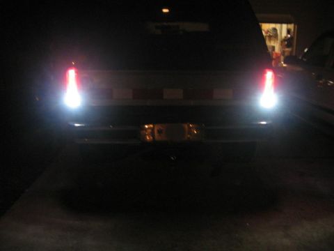 1988 Ford Bronco - This SUV's rear lights are illuminated at night, showing a boxy body style from the 1980s.