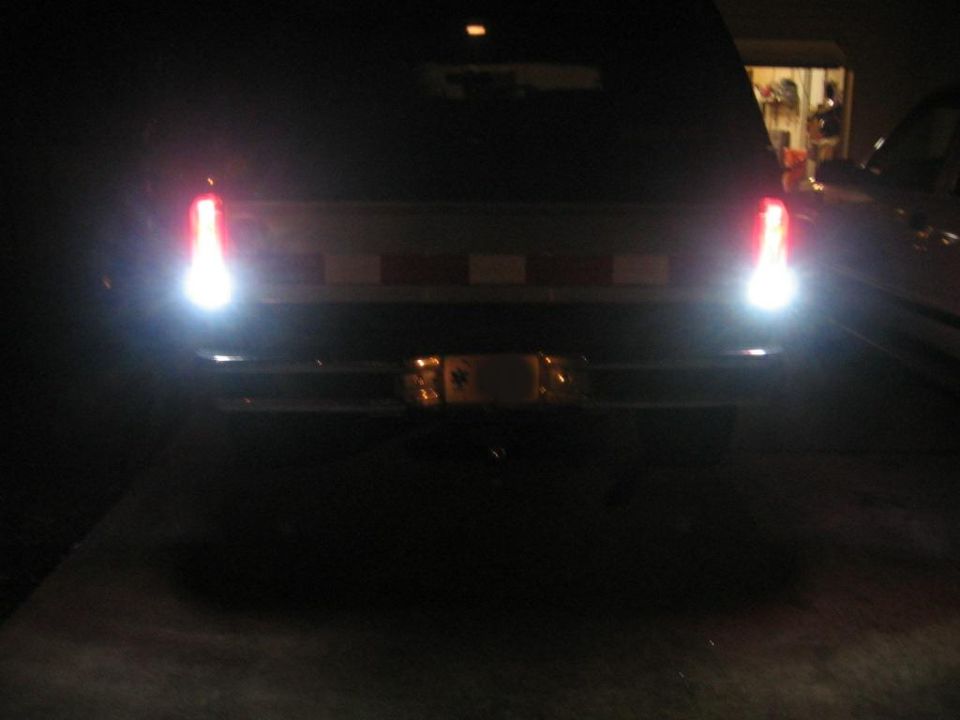 Rear view of a dark 1980s SUV with bright red tail lights illuminated