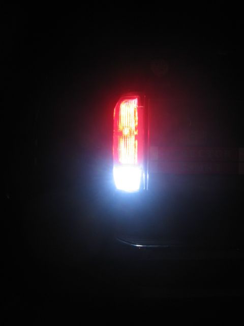 1988 Ford Bronco - The rear tail light assembly is visible, with the bright white reverse light illuminated against the dark background.