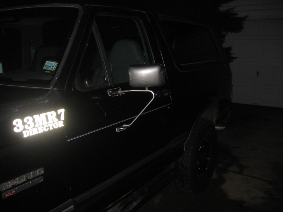Black Ford Bronco with "33MR7 DIRECTOR" text on the door, viewed from the front quarter