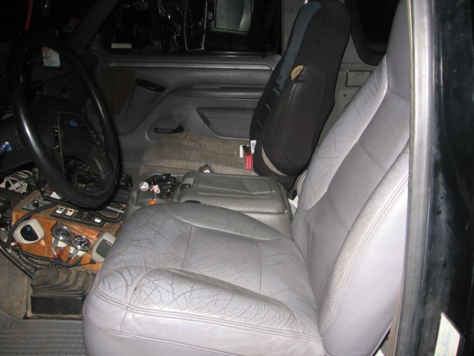 Interior view of a truck or SUV showing the driver's seat, dashboard, and center console. The seats are gray leather