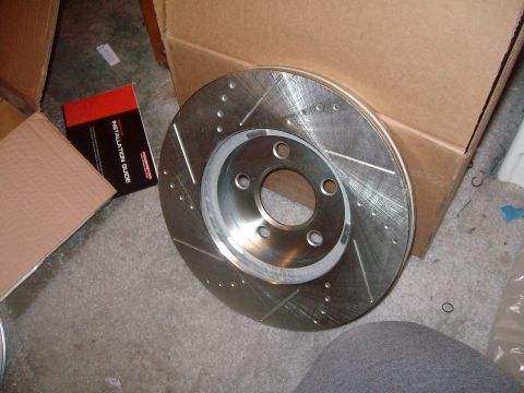 2004 Ford Crown Victoria - A new slotted and drilled brake rotor is shown with its installation guide and packaging.