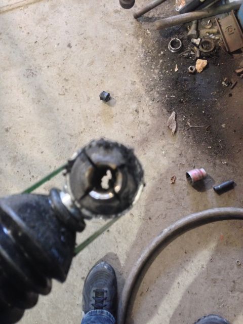 1979 Ford Bronco - A damaged CV joint boot and axle part is shown on a concrete floor with various tools and debris.