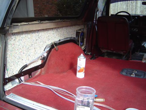 1986 Ford Bronco - Interior of a vehicle undergoing restoration, showing red carpet over the rear floor and transmission hump with exposed insulation and wiri…