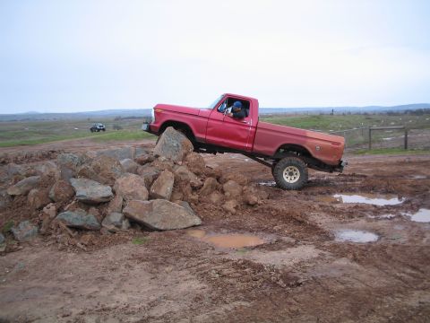 1976 Ford F-100 - 1976 Ford F-100 navigating a rocky obstacle during an off-road excursion.