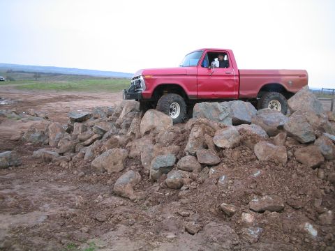 1976 Ford F-100 - A red pickup truck navigates a rocky obstacle course, its off-road capabilities.