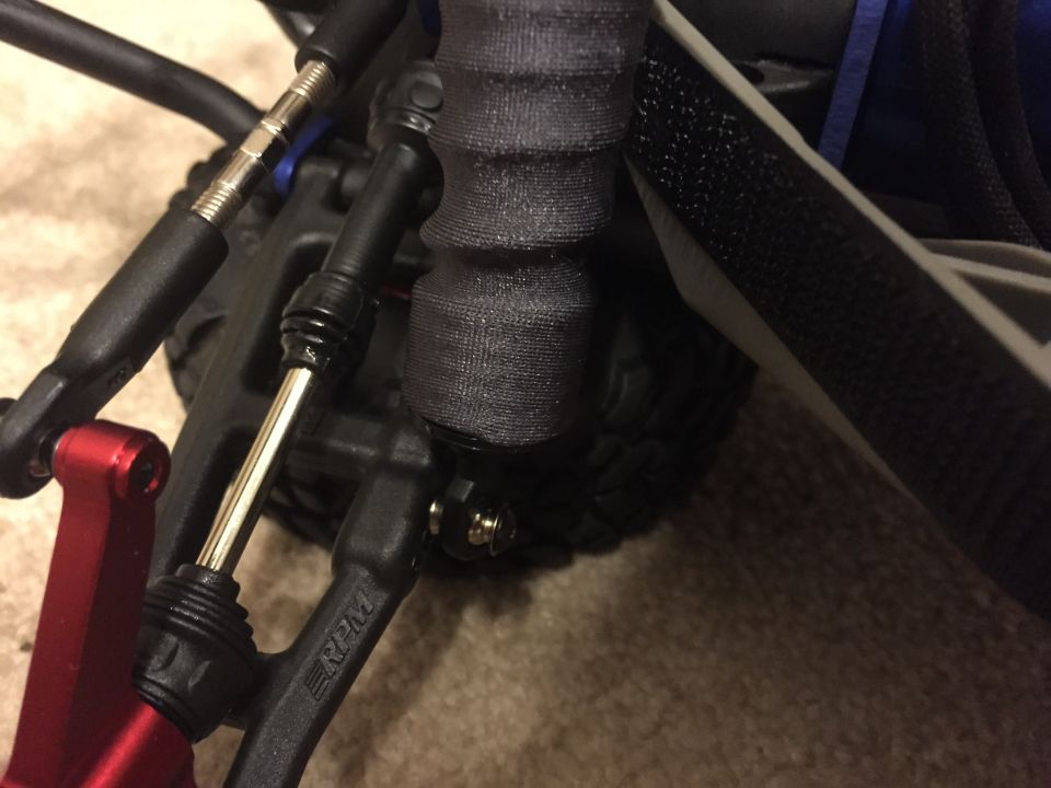 Close-up of a red suspension arm and black linkages on an RC car