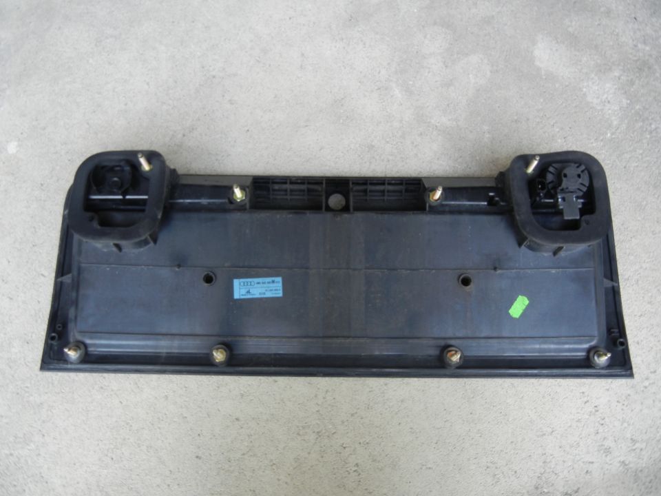 Black plastic rear license plate mounting bracket with two rubber grommets and visible screws