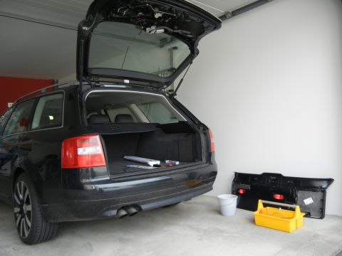 2003 Audi A6 - The rear of a black 2003 Audi A6 wagon is shown with its trunk open, next to a disassembled rear bumper and a toolbox.