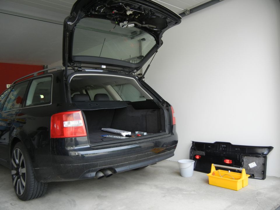 Black 2003 Audi A6 wagon with open trunk, parked in a garage. A removed rear bumper assembly and a yellow toolbox are on the floor