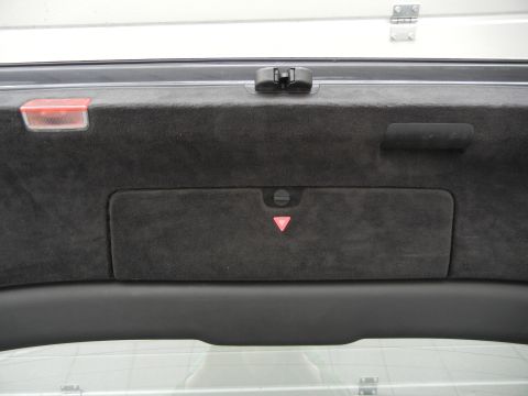 2003 Audi A6 - The interior of a car's trunk is visible, showing dark carpeting and a warning triangle emblem.