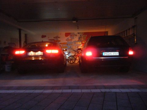 2003 Audi A6 - Two Audi sedans are parked in a garage, their brake lights illuminated.