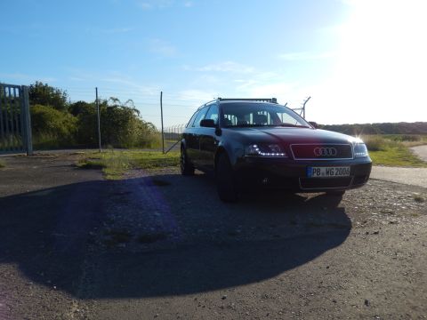 2003 Audi A6 - A black Audi A6 Avant is parked on a paved area under a clear blue sky, with a fence and vegetation in the background.