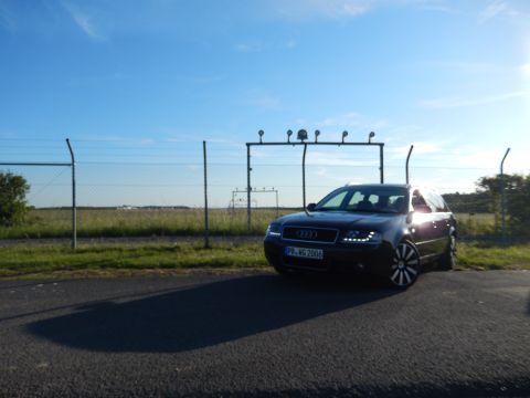2003 Audi A6 - A dark station wagon is parked near a fence under a clear blue sky. The license plate reads PB.MG 2006.