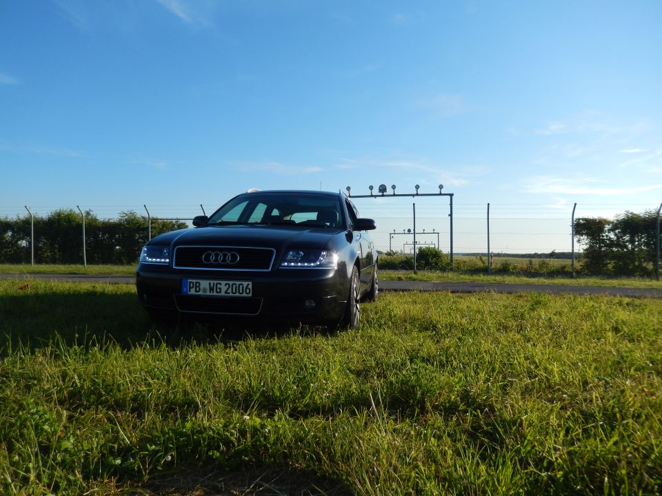 Black Audi A6 sedan parked in grassy field, front view. License plate reads PB WG 2006
