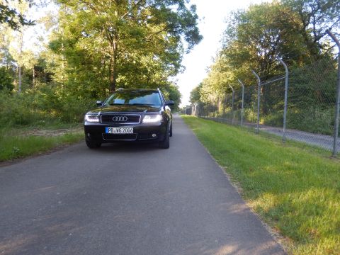 2003 Audi A6 - A black Audi A6 wagon is parked on a road next to a grassy area and a chain-link fence.
