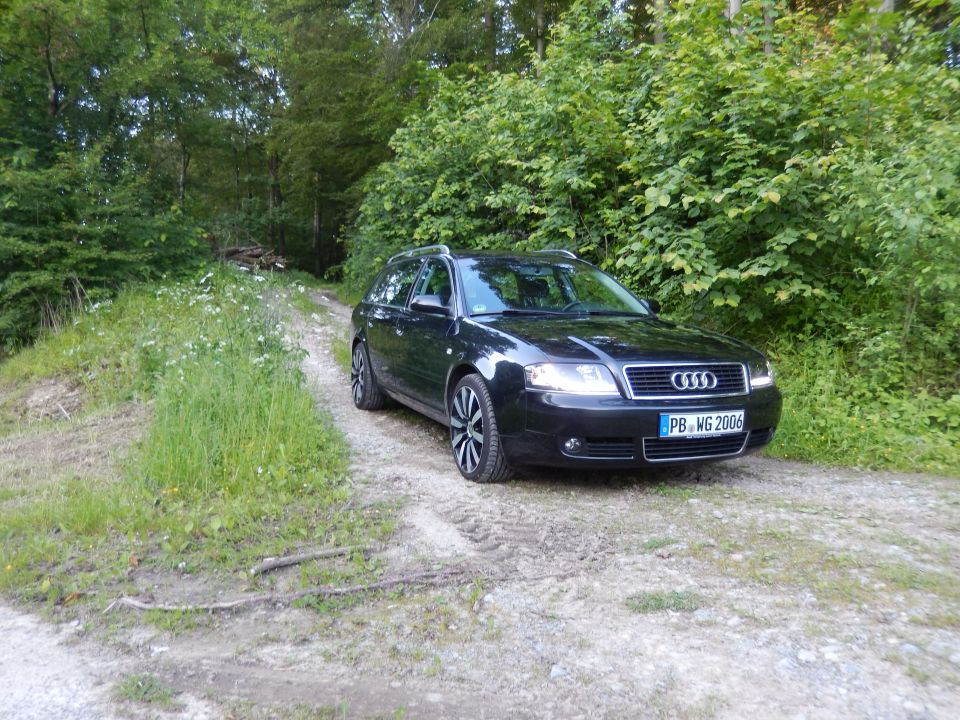 Black 2003 Audi A6 Avant parked on a dirt road with trees in the background