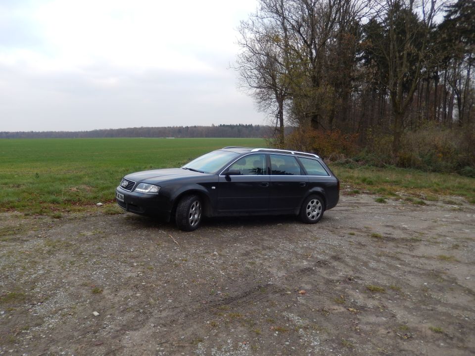 Black Audi A6 wagon parked on a dirt road next to a field