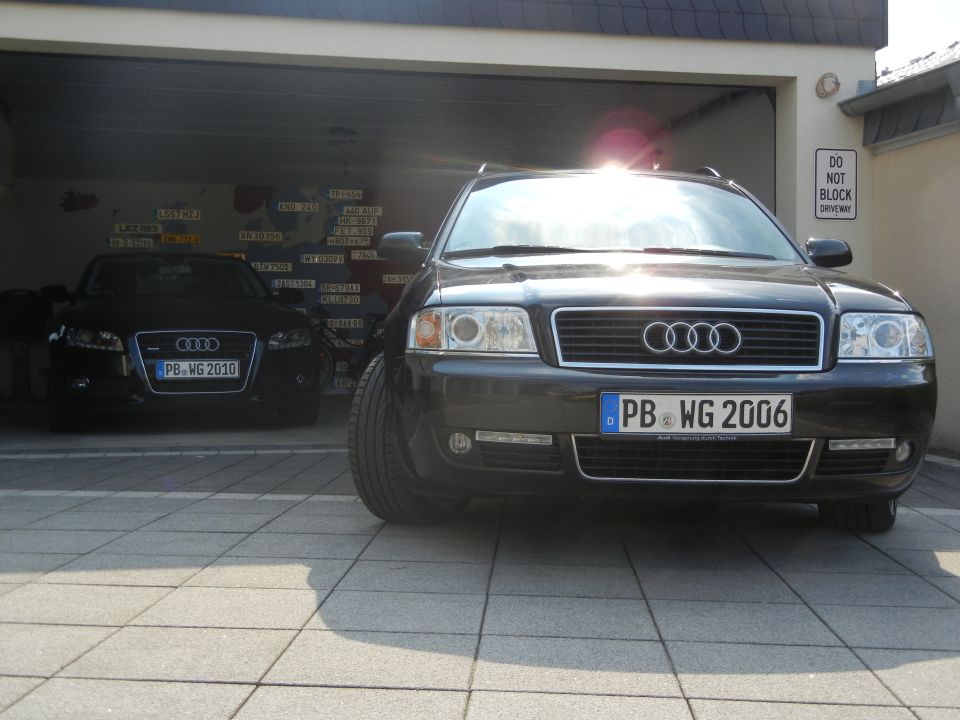 Front view of a black 2006 Audi A6 and a black Audi A4 parked in a garage