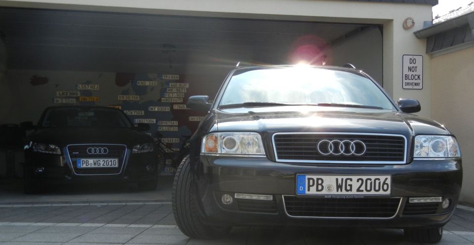 Two black Audi sedans parked in a garage. The front car has license plate PB WG 2006