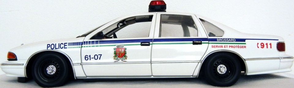 White police car with blue and green stripes, "POLICE" text, and "61-07" markings