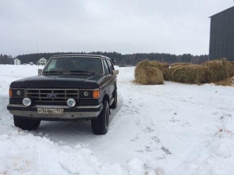 1987 Ford Bronco - 1987 Ford Bronco in a snowy field with hay bales and a barn.