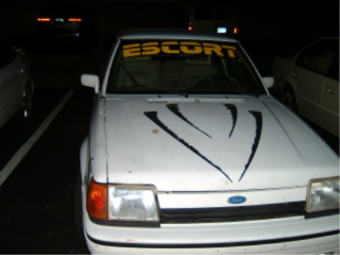 1997 Ford Taurus - White Ford Escort with "ESCORT" banner and hood decals. The claim of 1997 Ford Taurus is incorrect.