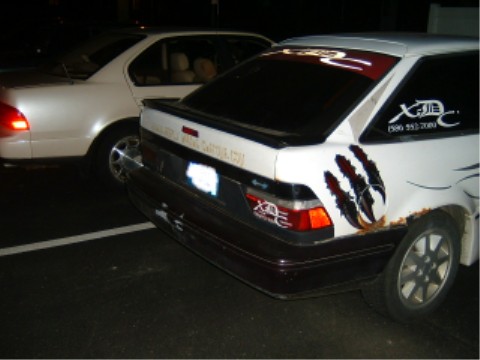1997 Ford Taurus - A modified sedan with custom decals and claw marks is parked next to another vehicle at night.