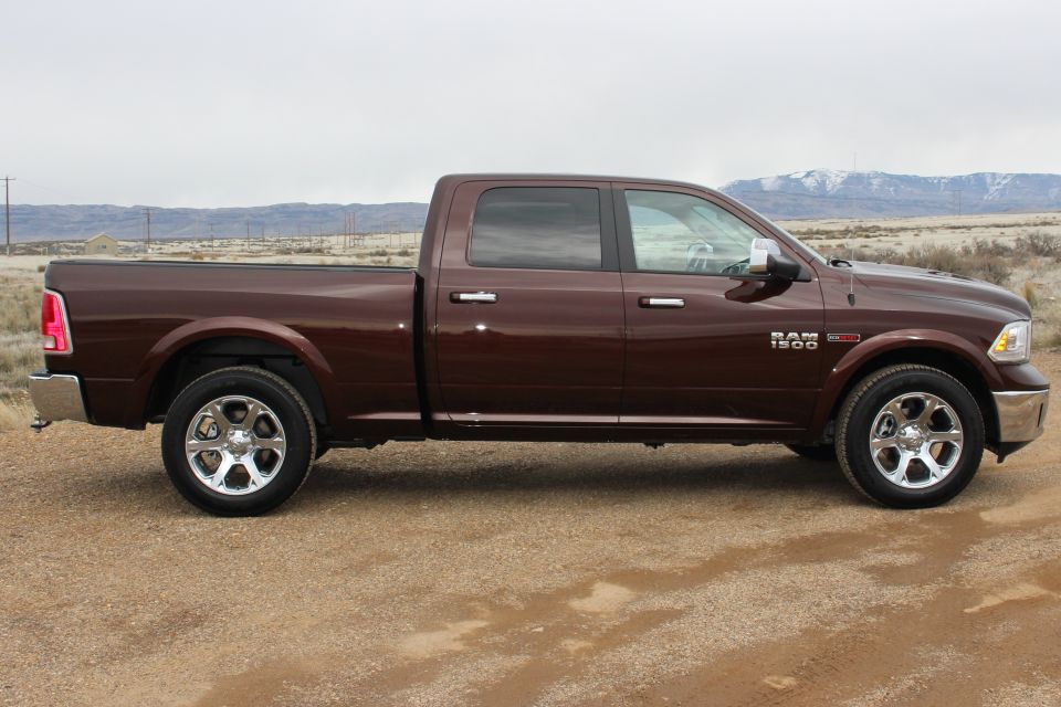 Side view of a brown 2015 Dodge Ram 1500 pickup truck parked on a dirt road