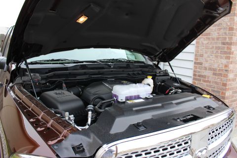 2015 Dodge 1500 - The engine bay of a pickup truck is shown with the hood raised, revealing the engine components and coolant reservoir.