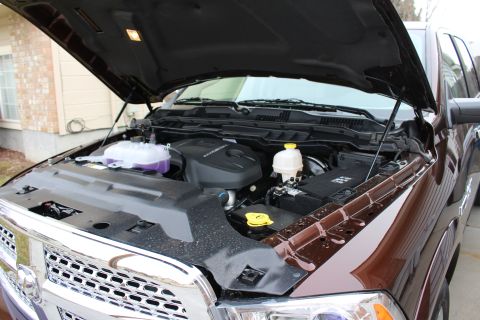 2015 Dodge 1500 - The engine bay of a brown Ram 1500 truck is visible with the hood raised, revealing the engine and front grille.