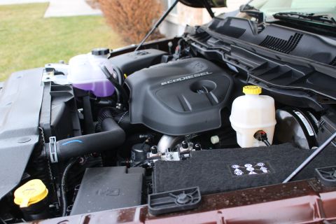 2015 Dodge 1500 - The engine bay of a truck, the EcoDiesel engine cover and various fluid reservoirs.