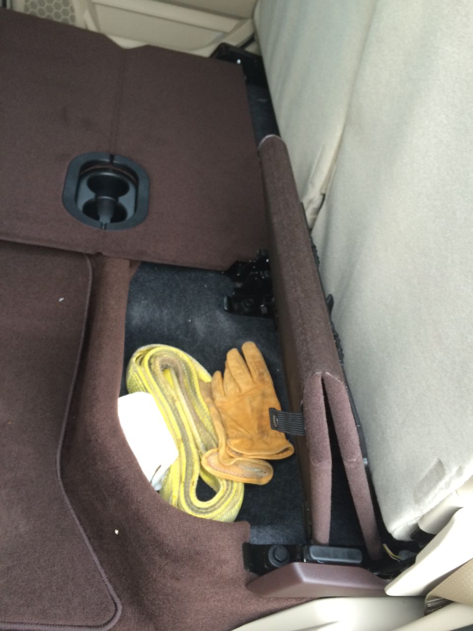 Interior storage compartment with a coiled yellow tow strap and brown work gloves