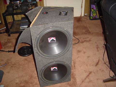 1986 Ford Bronco - This image shows a pair of Kicker subwoofers housed in a carpeted enclosure, with the Kicker logo clearly visible on each speaker.