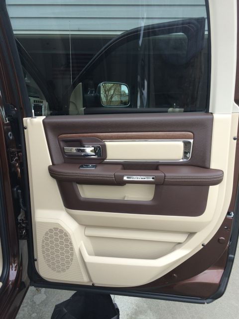 2015 Dodge 1500 - The interior door panel of a truck features two-tone brown and tan upholstery with chrome accents and a speaker grille.