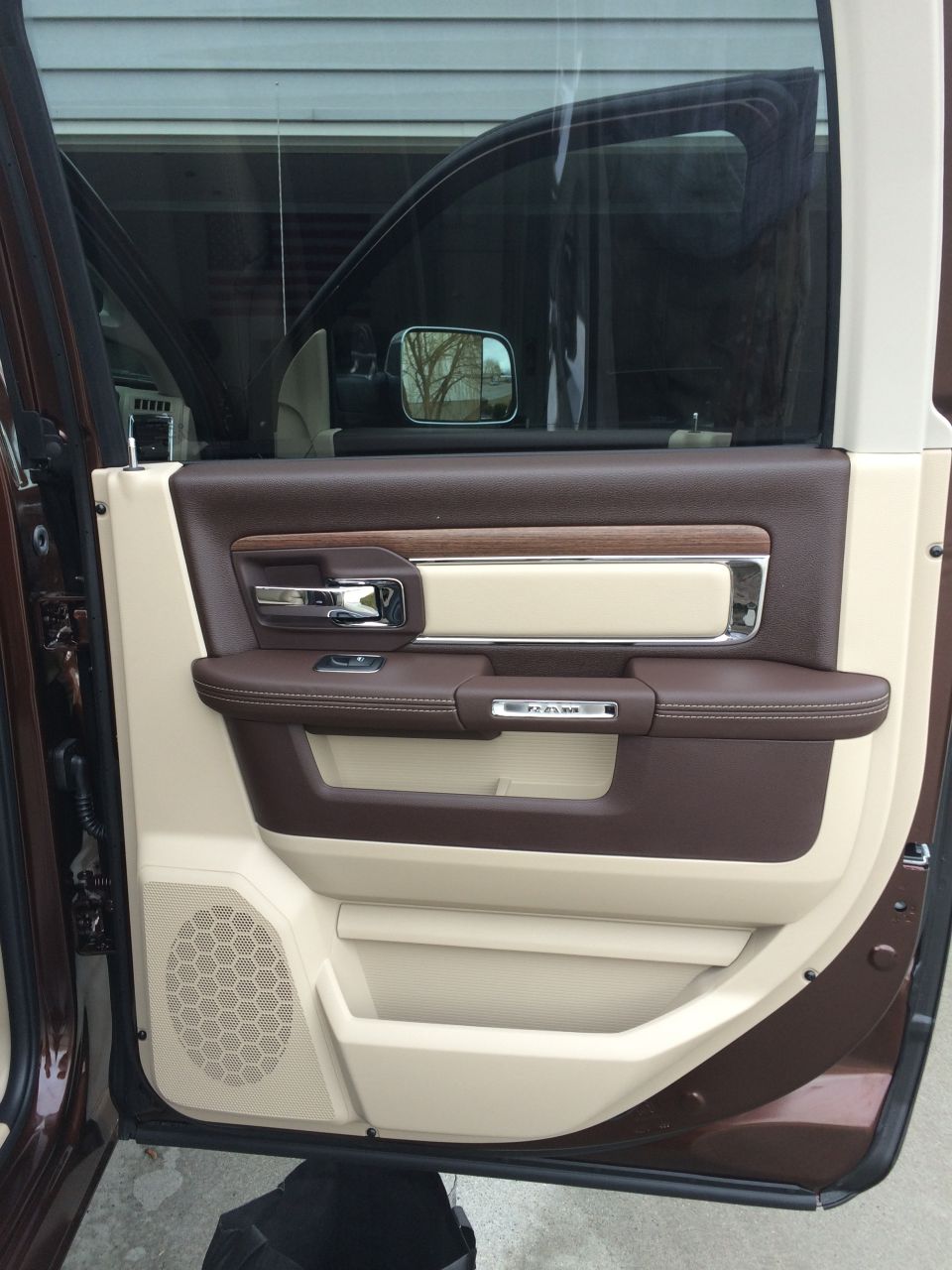 Interior of a truck door with brown and tan trim, chrome handle, and a speaker grille. The word 'RAM' is visible on the door panel