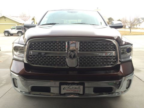 2015 Dodge 1500 - Front view of a brown 2015 Dodge 1500 pickup truck, its distinctive grille and headlights. A Jeep is parked in the background.