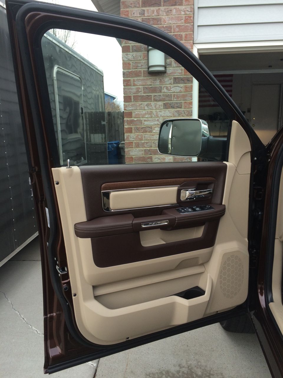 Interior of a truck door with brown and tan trim, showing the door panel, window controls, and side mirror