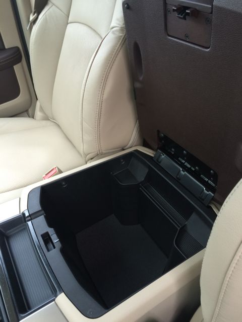 2015 Dodge 1500 - Open center console storage compartment in a 2015 Dodge 1500, with beige leather seats visible.