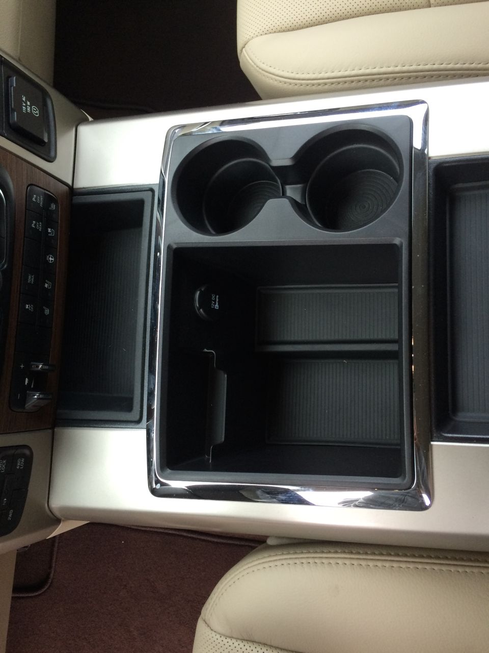 Interior shot of a truck's center console with cup holders and storage bins. Has a 12v power outlet
