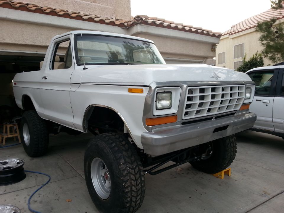 White 1979 Ford Bronco with lifted suspension and large tires, front 3/4 view