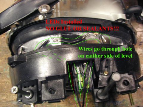 1998 Ford Taurus - Close-up of a car headlight assembly showing wiring modifications and installation notes.