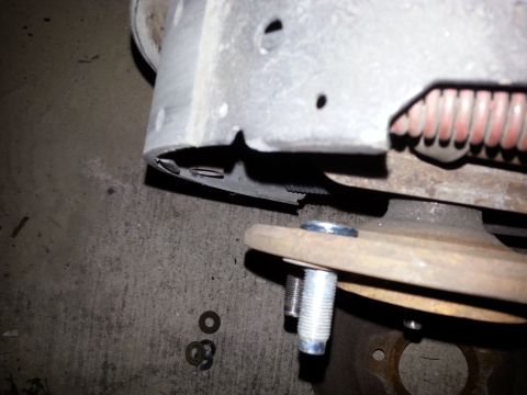 1992 Ford Bronco - Close-up view of a wheel stud and brake drum assembly, with washers scattered on the concrete surface.