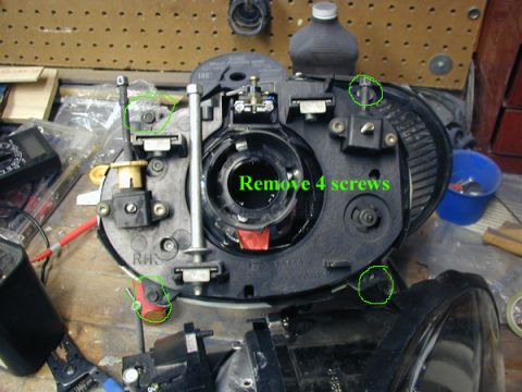 1998 Ford Taurus - Close-up of a vehicle headlight assembly with instructions to remove four screws highlighted.