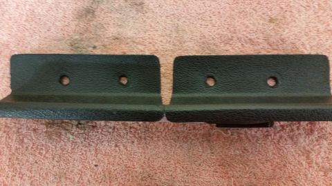 2015 Chevrolet new - Two black plastic trim pieces are shown, each with two screw holes, against a textured pink background.
