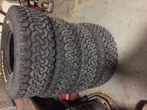 1994 Ford Bronco - Four BFGoodrich All-Terrain T/A tires are stacked in a garage setting.