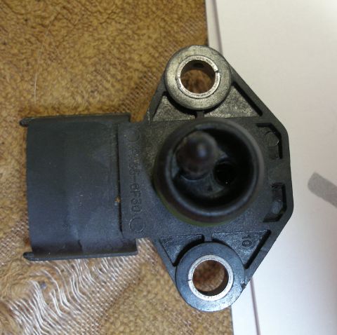 2010 Hyundai Genesis - Close-up of a black plastic electrical sensor, possibly a MAP sensor, showing mounting points and part number markings.